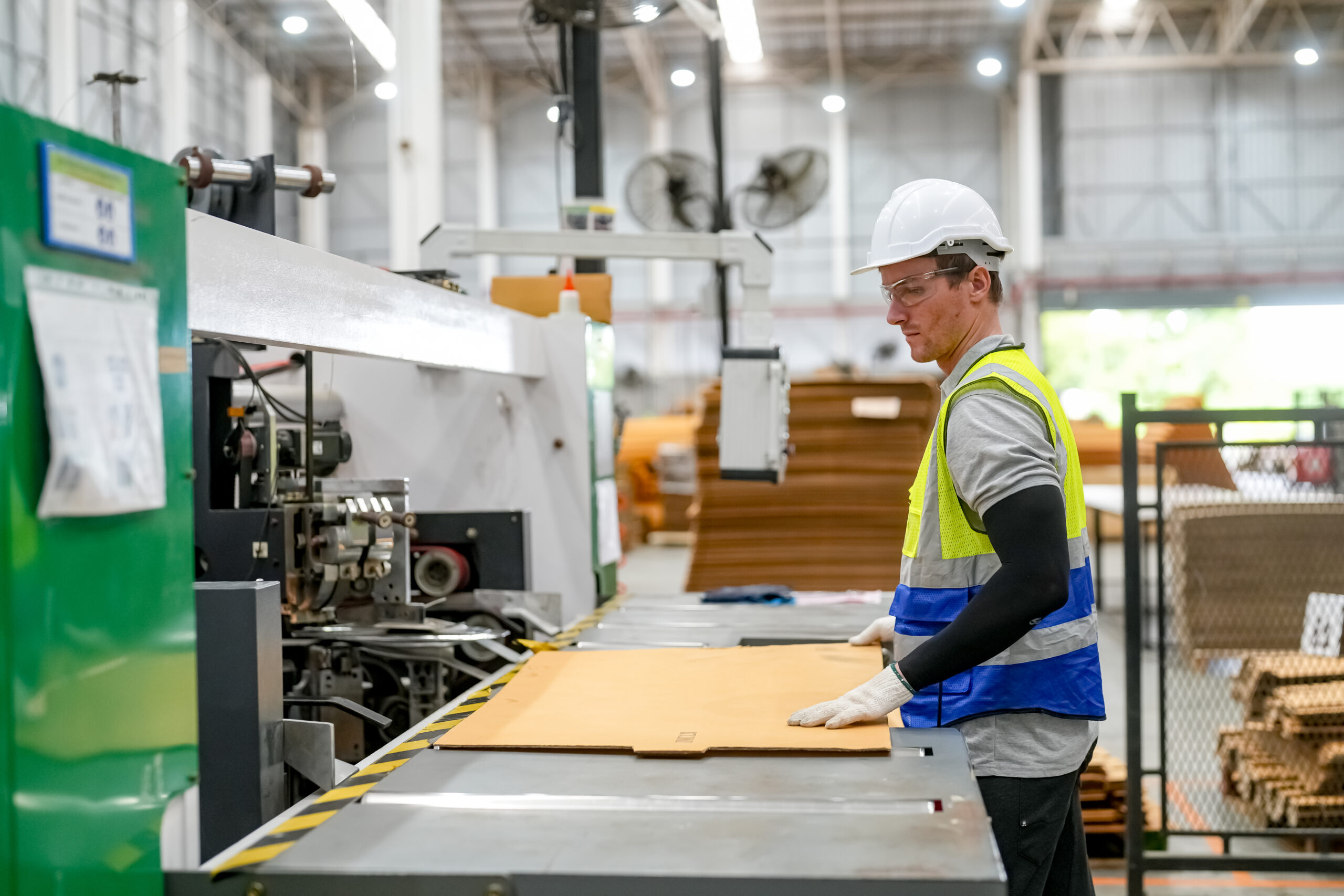 Industrial worker indoors in factory. Young technician with orange hard hat. Smart Caucasian factory worker wearing hardhat and working in power plant.