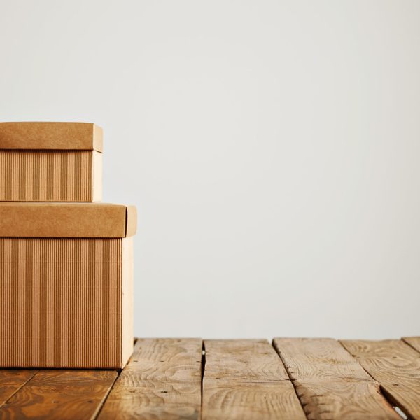 Two different sized beige corrugated cardboard unlabeled boxes presented on top of each other isolated on white